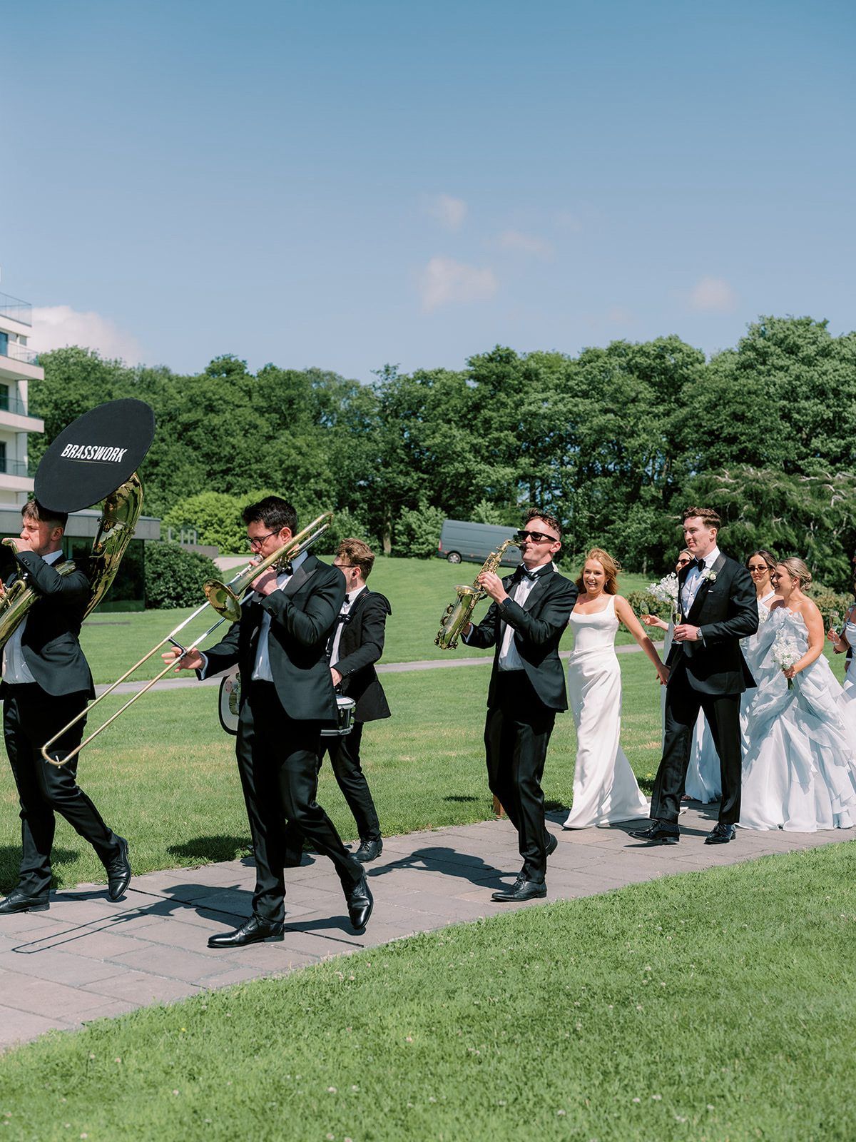 Brasswork marching with the couple and guests following